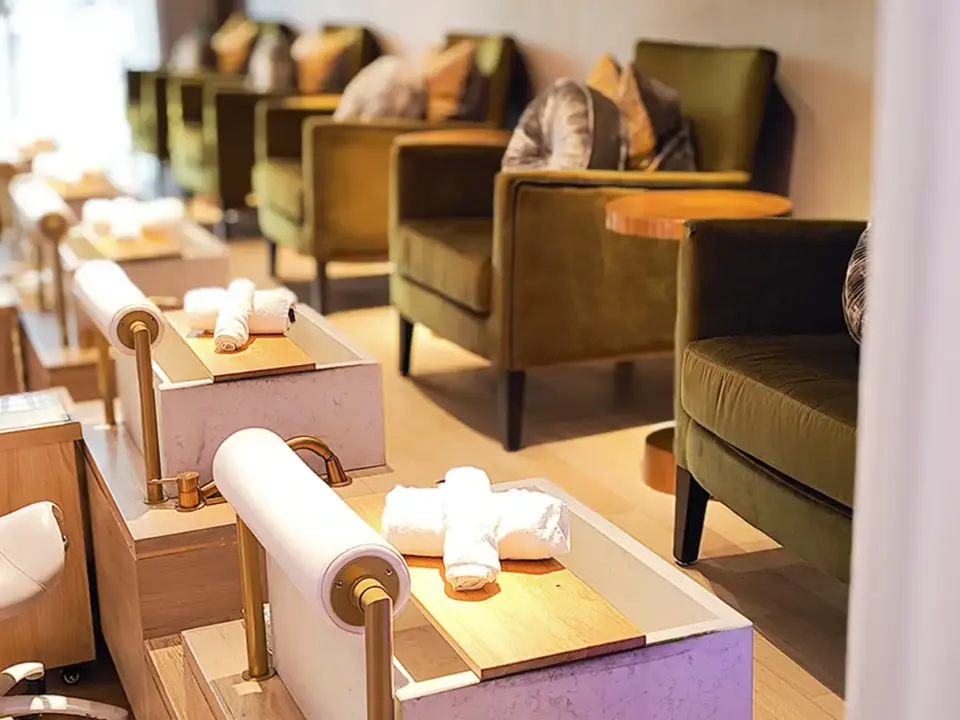 Gast erhält am Pool eine Handmassage, im Hintergrund Obst und Smoothies.